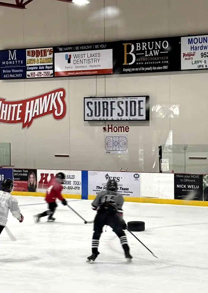 Bruno Law sponsor board above the ice at Thaler Ice Arena during a youth hockey game